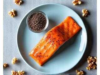 Filetes de salmón fresco, semillas de chía y linaza en pequeños tazones, y nueces enteras.