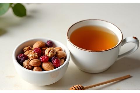 Un pequeño tazón con una mezcla de nueces, almendras y frutos secos, junto a una taza humeante de té de manzanilla.